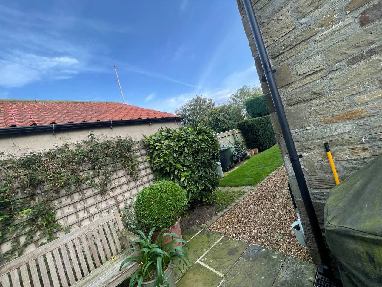 A tidy garden with clipped hedges, a gravel path and a neat lawn